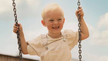 A child on a swing with a clear sky in the background.
