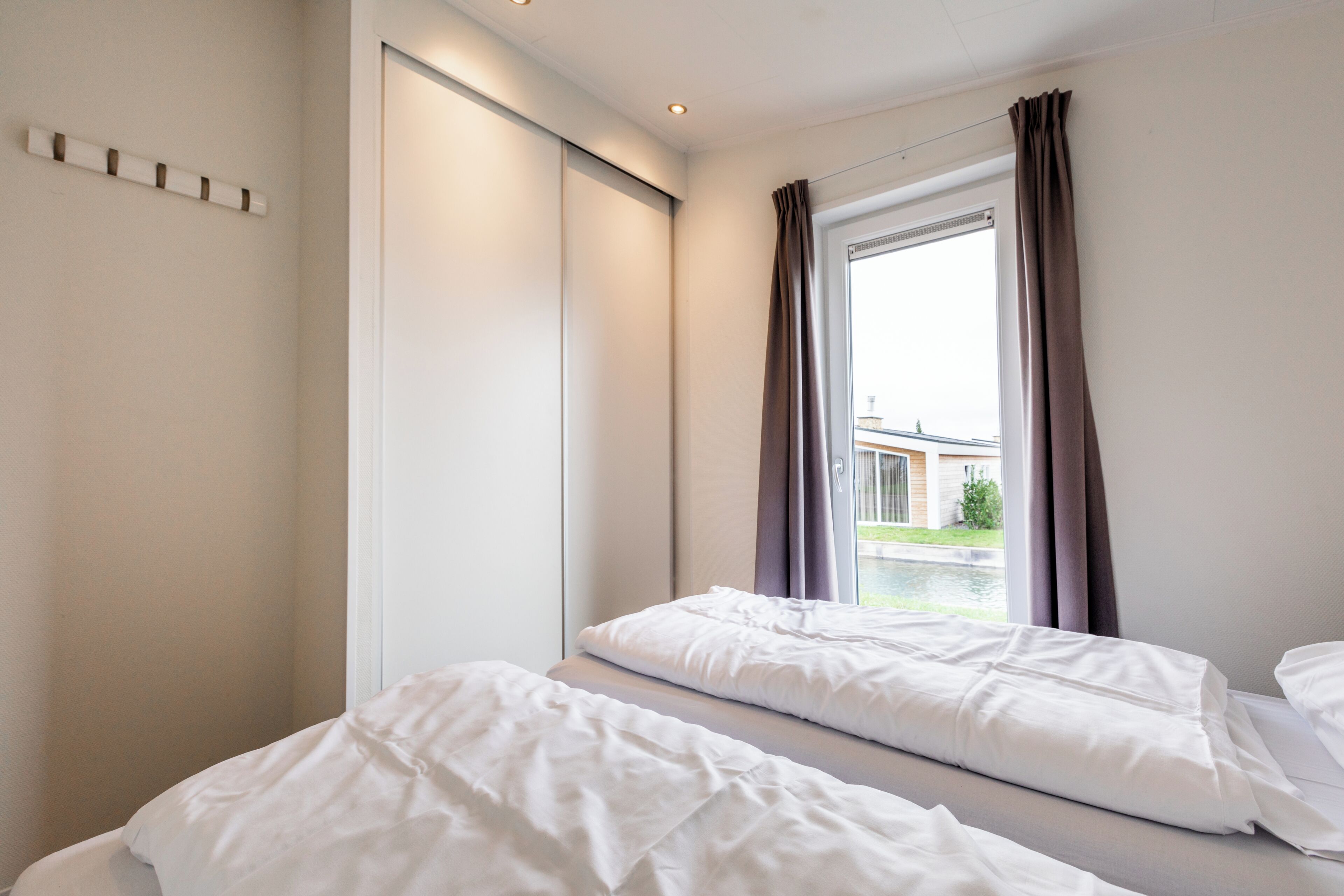 A hotel room with two beds, a sliding door, and a window with curtains.