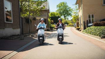 Deux personnes sur des scooters dans une rue résidentielle.