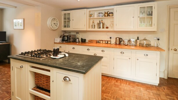 A kitchen with white cabinets, a stove, and various appliances.