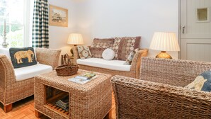 A cozy living room with wicker furniture, a white sofa, and two lamps.