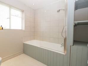 A modern bathroom with a freestanding bathtub, a shower, and a window with blinds. - Downton Lodge (Lymington)