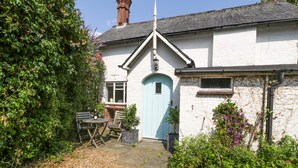 A white building with a blue door, a garden with gravel path, and outdoor furniture.