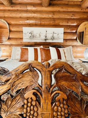 A log cabin interior with a bed, pillows, and a wooden headboard.