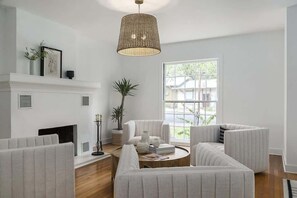 Ein modernes Wohnzimmer mit Kamin, weißen Möbeln und einem großen Fenster.