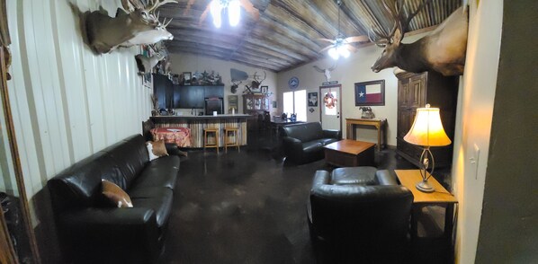 Relax in a traditional living area with a leather sofa, wooden coffee table, and mounted animal heads, perfect for socializing.