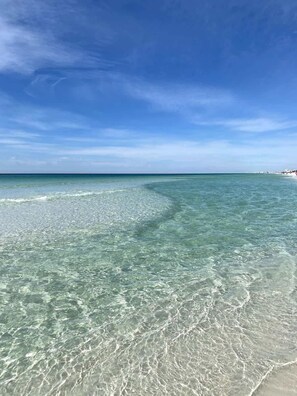 A clear view of a beach with shallow waters and a distant shoreline.
