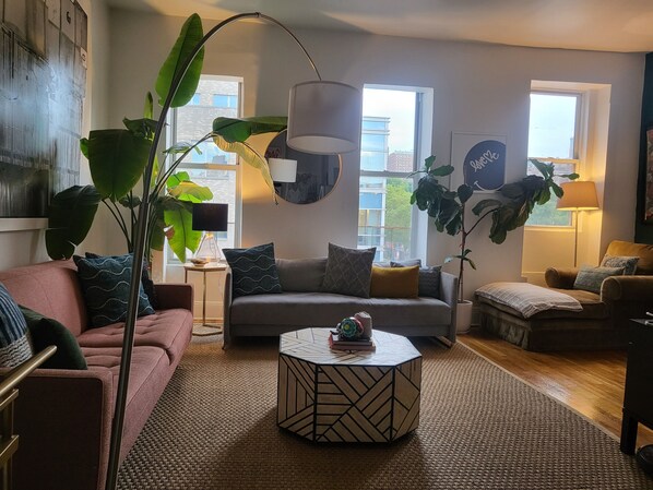 Relax in a cozy living space with a comfortable sofa, round coffee table, and lush green plants.