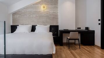 A modern hotel room with a large bed, a desk, and a chair.