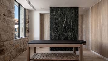 Un interior moderno con una mesa y un banco de madera, una pared de piedra y un ventanal grande.