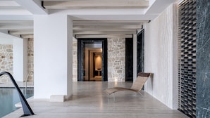 A modern interior with a pool, stone walls, and a lounge area.