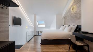 A modern bedroom with a large bed, a desk, and a television.