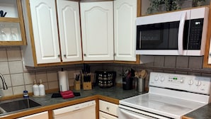 A kitchen with white cabinets, a microwave, an oven, and a sink.