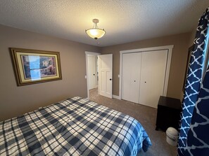 Ein Schlafzimmer mit Bett, Deckenleuchte, Tür und Kleiderschrank.