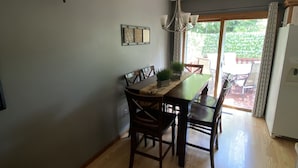 A dining area with a wooden table and chairs, a chandelier, and a clock on the wall.