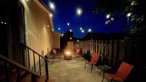 An outdoor patio with a fire pit, seating, and a wooden fence.
