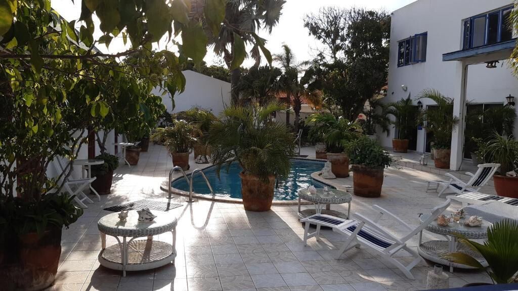 A poolside area with lounge chairs, a small round table, and potted plants.