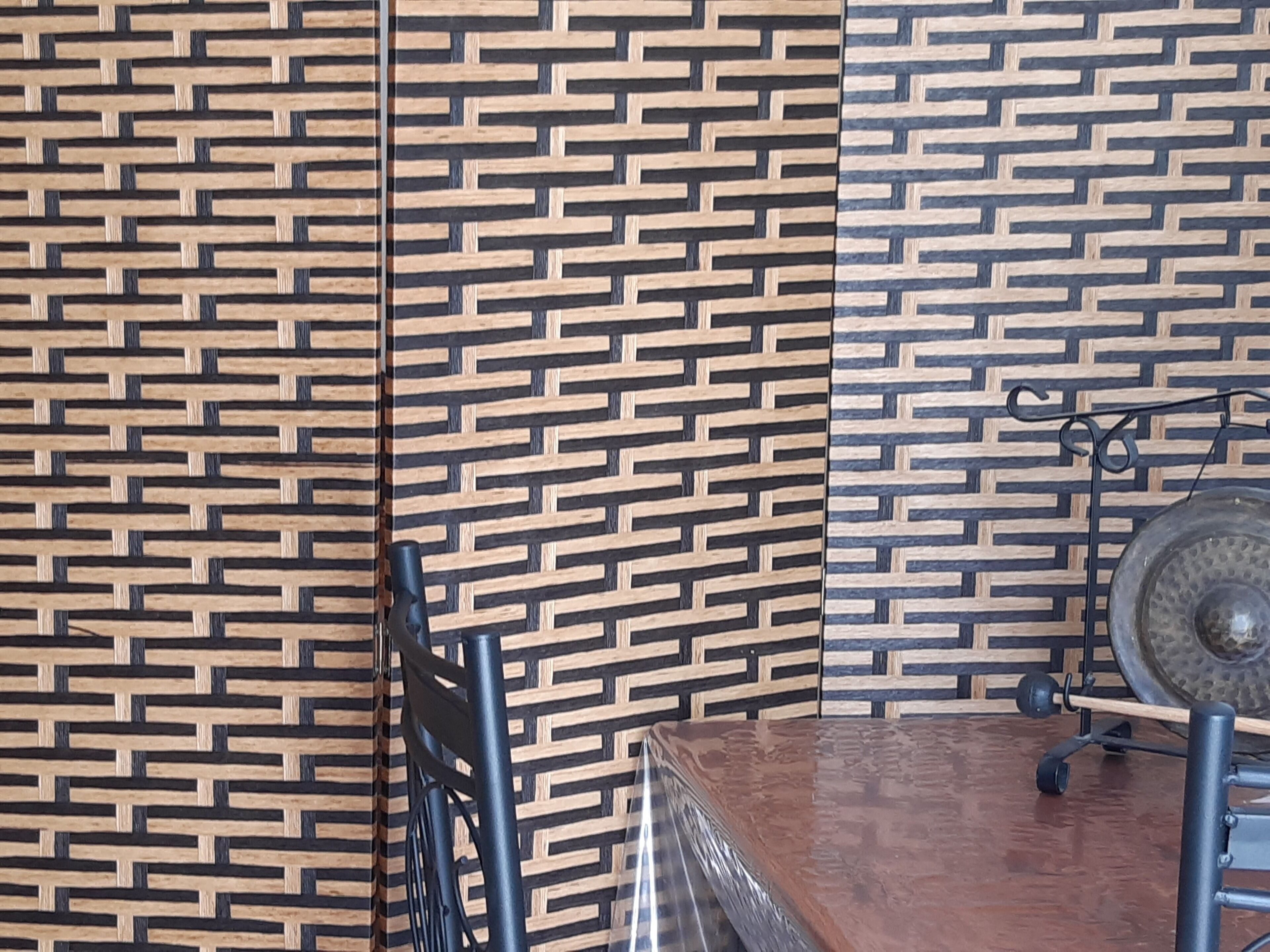 Una habitación con un papel tapiz estampado, una mesa de madera y una silla.