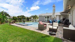 A backyard with a swimming pool, patio furniture, and a covered grill area. - Waterfront Retreat in the Heart of Tampa. Close to TPA, RayJay and Steinbrenner (Tampa)