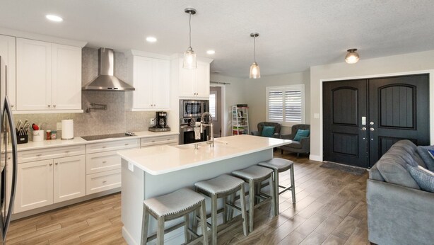 A modern kitchen with white cabinets, a central island with stools, stainless steel appliances, and pendant lighting. - Waterfront Retreat in the Heart of Tampa. Close to TPA, RayJay and Steinbrenner (Tampa)