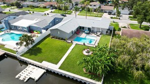 A residential property with a large swimming pool, a well-maintained lawn, and a dock extending into a body of water. - Waterfront Retreat in the Heart of Tampa. Close to TPA, RayJay and Steinbrenner (Tampa)