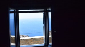 A view through a window with a clear view of the sea and rocky coastline.