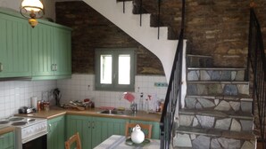 A kitchen with green cabinets, a stone staircase, and a dining table with chairs.