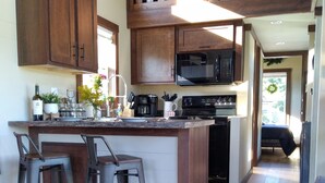 A kitchen with wooden cabinets, a central island with bar stools, a microwave, and a stove. - Summer Fun in Blue Ridge☀️Mins from Downtown Activities  (Morganton)