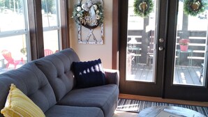 A living room with a grey sofa, a small round table, and a door with glass panels. - Summer Fun in Blue Ridge☀️Mins from Downtown Activities  (Morganton)