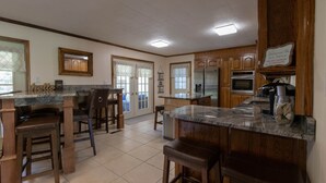 A spacious kitchen with wooden cabinets, a marble countertop, and a bar area with stools.