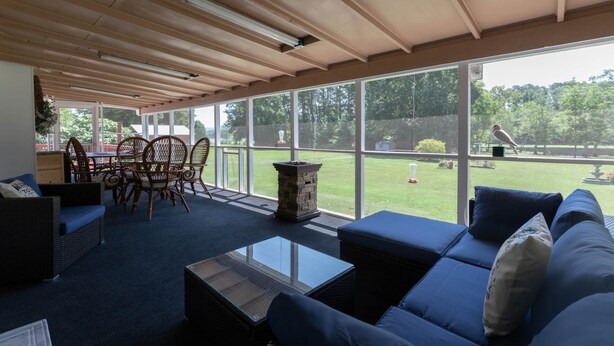 A spacious indoor area with a large window, a dining table with chairs, and a seating area with sofas and a coffee table.