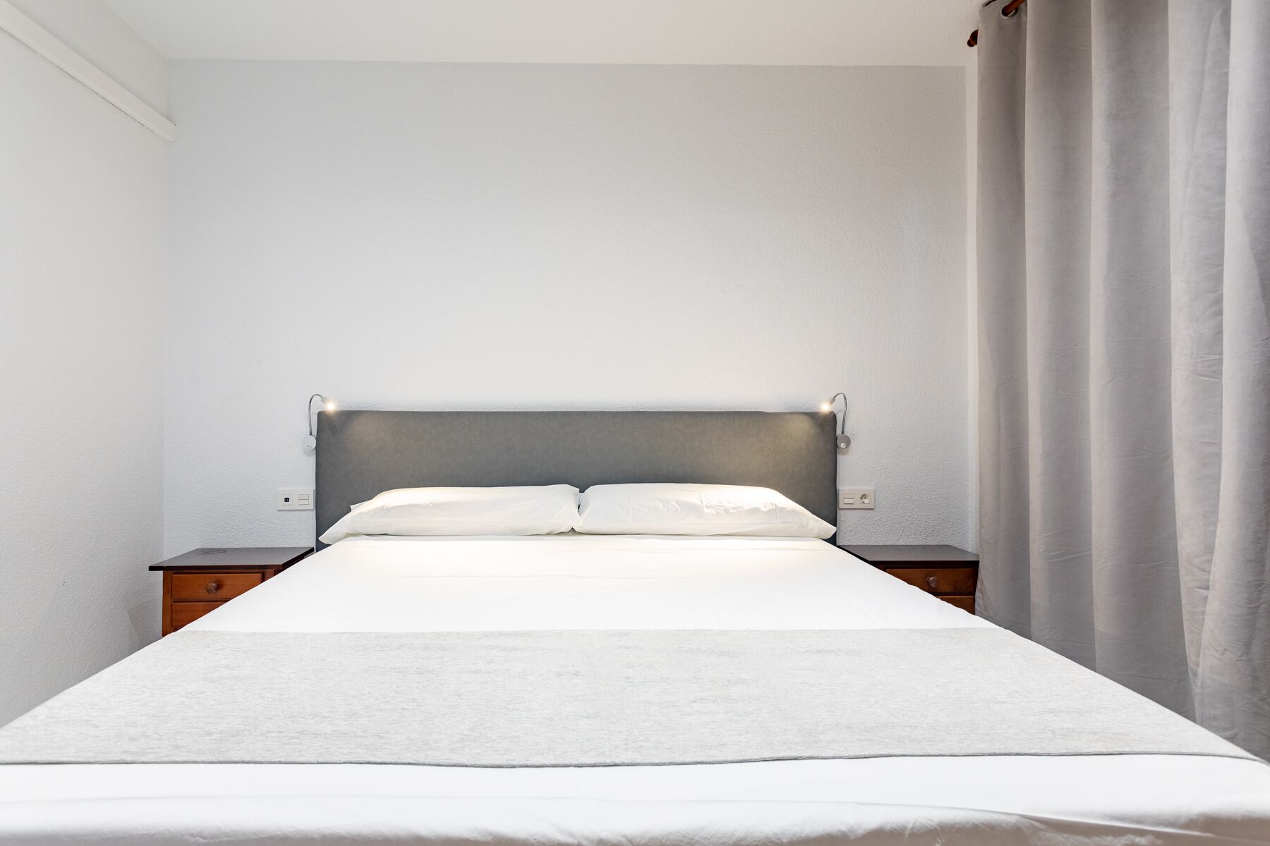 Una camera da letto con un letto, comodini e una tenda.