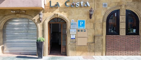 Ein Gebäude mit einem Schild, auf dem "La Costa" steht, und einem heruntergelassenen Metallrollladen auf der linken Seite.