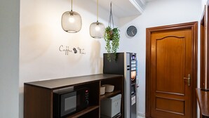 A kitchen with a microwave, a coffee machine, and a clock on the wall. - Hostal La Costa (El Ejido)