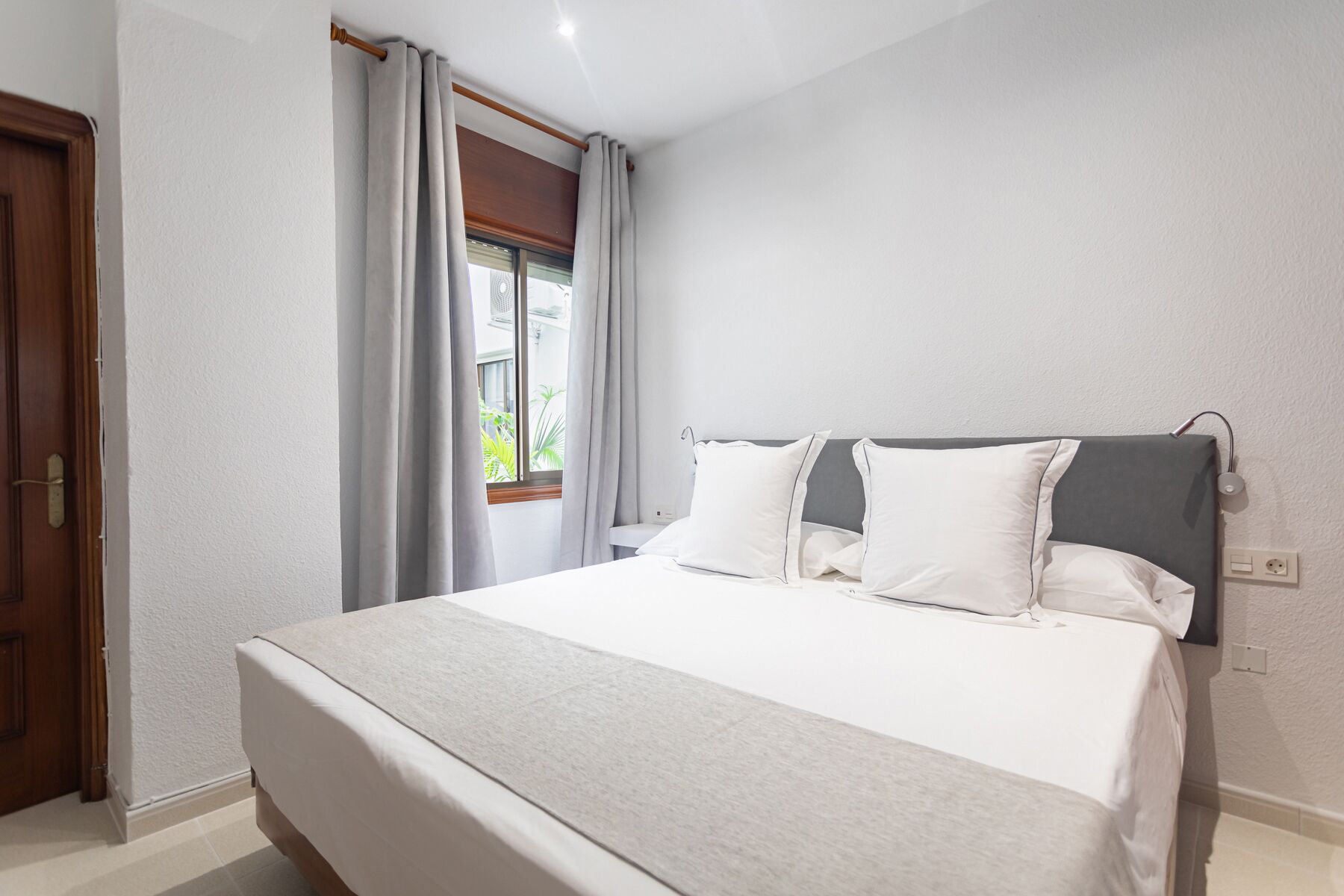 Un dormitorio con cama, cortinas, ventana y puerta.