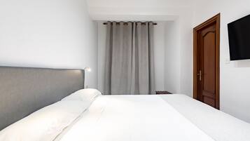 Un dormitorio con una cama, una puerta de madera y una cortina.