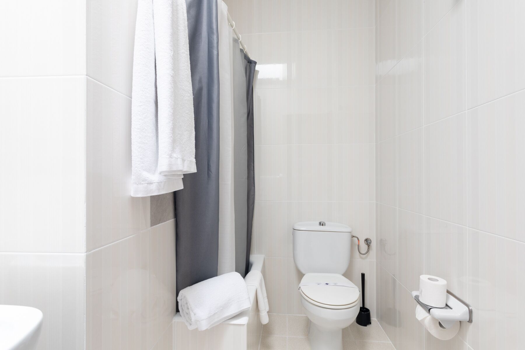 Et moderne badeværelse med toilet, badeforhæng og toiletpapirholder.