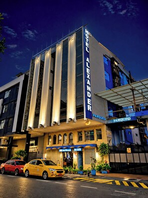 A hotel with a prominent vertical sign reading 'HOTEL ALEXANDER PARQUEO' and a visible entrance with a canopy. - Hotel GH Alexander (Guayaquil)