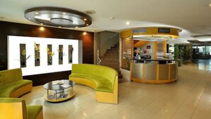 Un hall d’entrée moderne avec un canapé jaune incurvé, un comptoir d’accueil et un escalier.