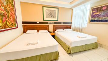 A hotel room with two single beds, a nightstand, a framed picture above the beds, and a painting on the wall.