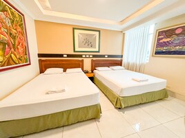Habitación de hotel con dos camas individuales, una mesita de noche, un cuadro enmarcado sobre las camas y un cuadro en la pared.