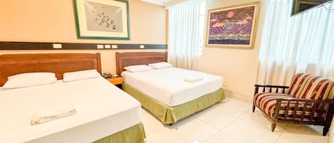 A hotel room with two beds, a chair, a painting, and a television.