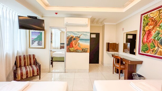 Une chambre d’hôtel avec deux lits, une télévision, un tableau et un bureau.