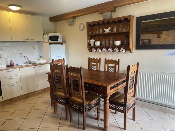 A kitchen with wooden cabinets, a microwave, a sink, and a dining table with chairs.