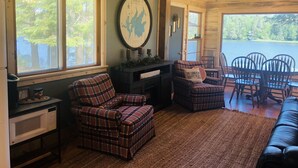 A cozy cabin interior with plaid furniture, a map on the wall, and a view of a lake.