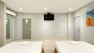 A hotel room with two beds, a flat-screen TV mounted on the wall, and a painting on the wall.