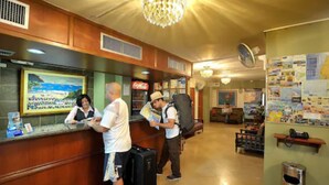 A reception area with a wooden counter, a large chandelier, and a wall with a map and various notices. - Hotel GH Sander (Guayaquil)