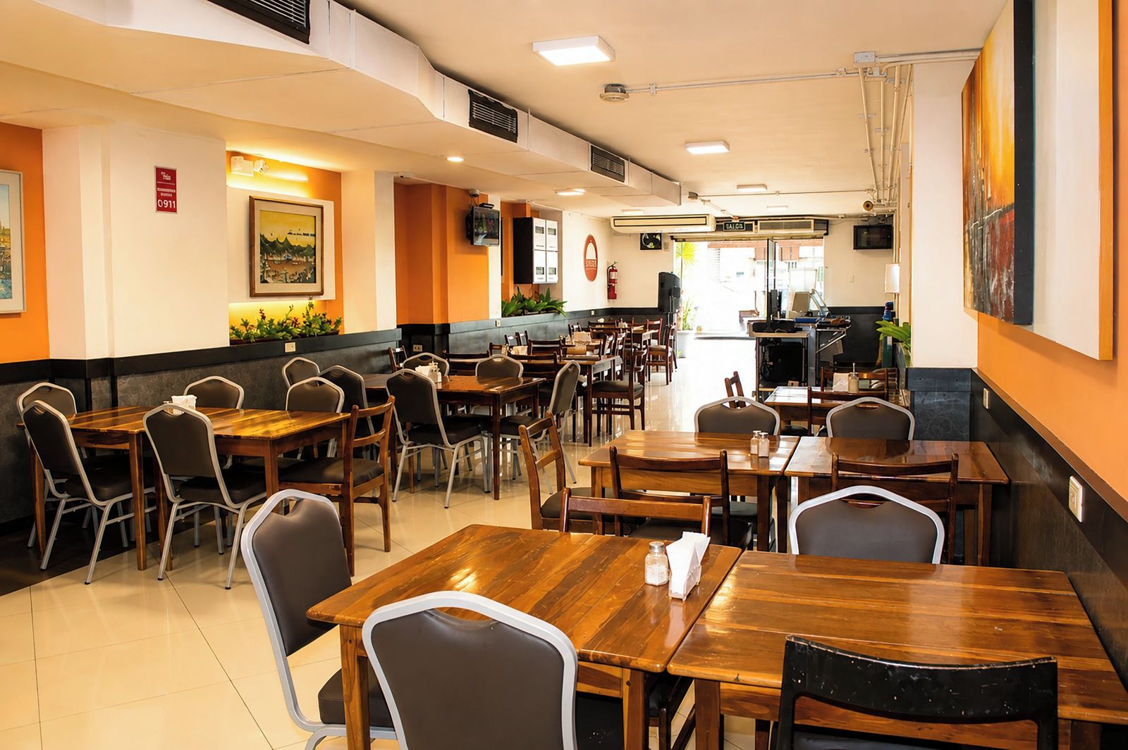 A restaurant with multiple tables and chairs, a counter, and a fire extinguisher on the wall.