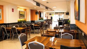 A restaurant with multiple tables and chairs, a counter, and a fire extinguisher on the wall.