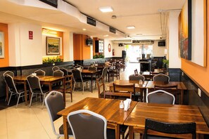 Un restaurante con varias mesas y sillas, una barra y un extintor en la pared.